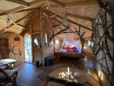 Cabane en bois cosy avec lit douillet et décoration naturelle. Ambiance chaleureuse.