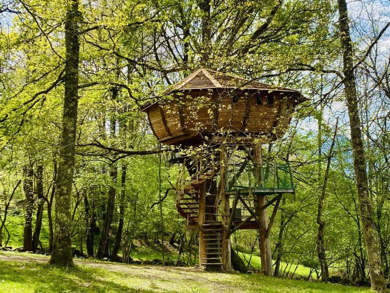 Cabane perchée en bois, entourée darbres verdoyants à Midi-Pyrénées.