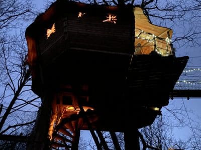 Cabane dans les arbres illuminée, perchée au cœur de la forêt en Midi-Pyrénées.