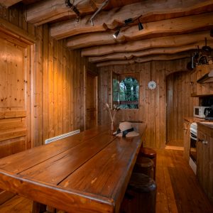 Cabane en bois dans les arbres, intérieur chaleureux avec table en bois massif.