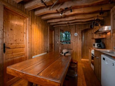 Cabane en bois dans les arbres, intérieur chaleureux avec table en bois massif.