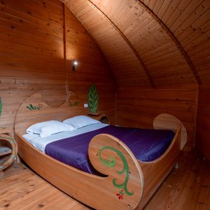 Hébergement insolite en Nouvelle-Aquitaine : chambre en bois avec lit original et décor végétal.