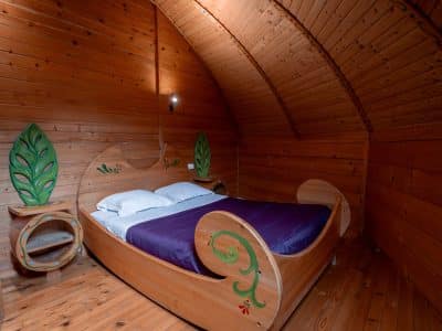 Hébergement insolite en Nouvelle-Aquitaine : chambre en bois avec lit original et décor végétal.