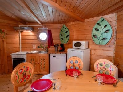Cabane en bois colorée en Nouvelle-Aquitaine, avec cuisine équipée et décor végétal.