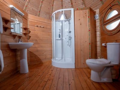 Intérieur dun hébergement insolite en bois avec douche moderne et décor chaleureux.
