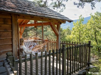 Cabane perchée en bois avec terrasse, vue sur la nature verdoyante en Provence.