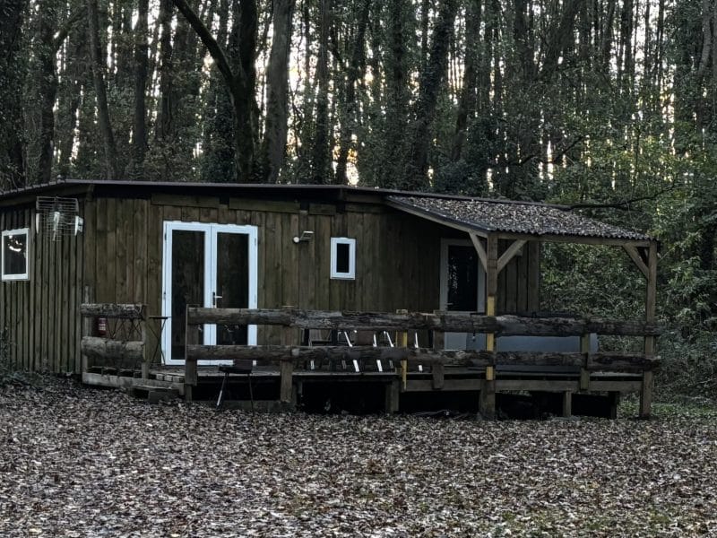 Cabane en bois au cœur des bois, avec terrasse en bois et vue sur la nature.