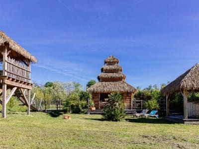 Hébergement insolite en Aquitaine : cabane en bois avec toit de chaume sous un ciel bleu.