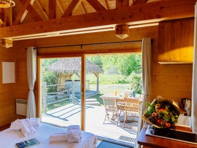 Cabane en bois avec vue sur la nature et terrasse ensoleillée.