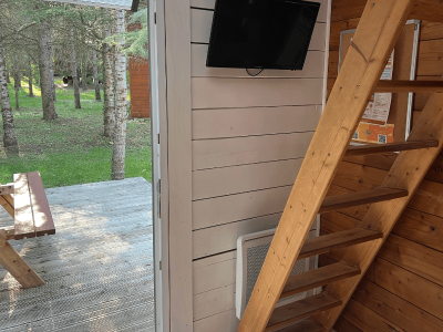 Cabane en bois dans les arbres, avec un escalier en bois et vue sur la forêt.