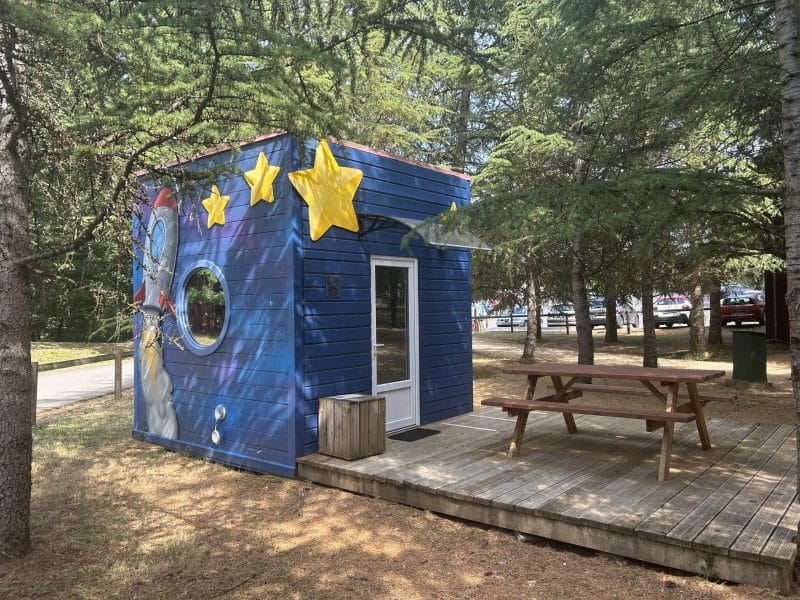 Cabane colorée en bois avec décor étoilé, située en pleine nature en Nouvelle-Aquitaine.