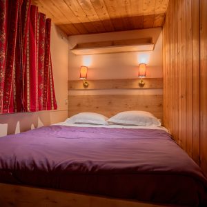Chambre cocooning en bois avec lit douillet et rideaux colorés en Nouvelle-Aquitaine.