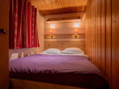 Chambre cocooning en bois avec lit douillet et rideaux colorés en Nouvelle-Aquitaine.