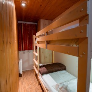 Chalet en bois avec lits superposés, ambiance chaleureuse et décor rustique.