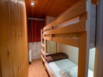 Chalet en bois avec lits superposés, ambiance chaleureuse et décor rustique.