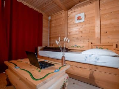 Chalet en bois douillet avec lit simple et décor coloré, idéal pour un séjour unique.