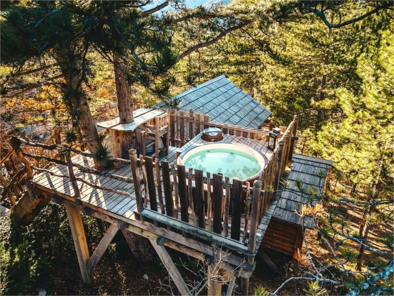 Cabane perchée en bois avec jacuzzi, entourée de pins en Provence-Alpes-Côte dAzur.