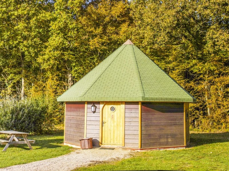 Cabane en bois avec toit vert, entourée de verdure en Nouvelle-Aquitaine.