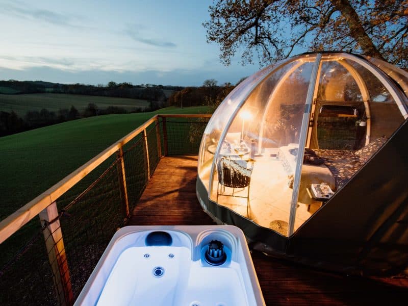Dôme transparent avec jacuzzi, offrant une vue panoramique sur la nature environnante.