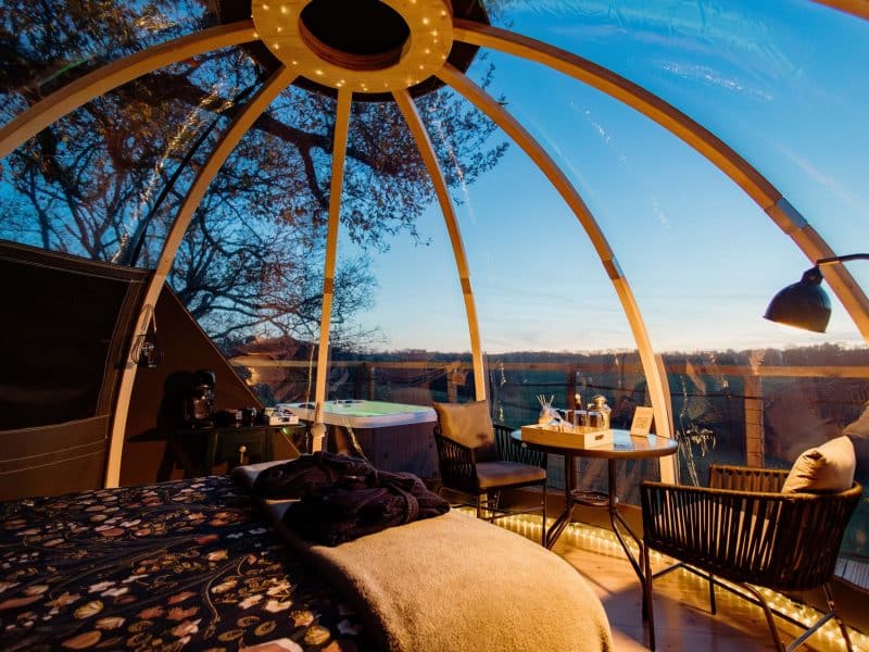 Dôme transparent avec vue panoramique, lit confortable et jacuzzi à lextérieur.