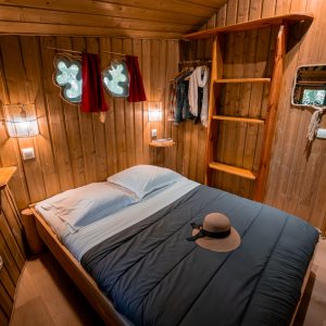 Chalet en bois chaleureux avec lit douillet et fenêtres en forme de cœur.