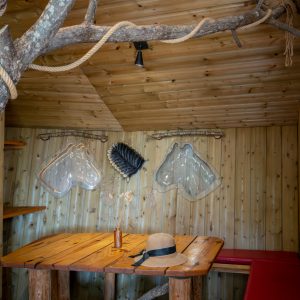 Cabane en bois dans les arbres, avec une table en bois et des décorations naturelles.
