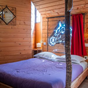Cabane en bois avec un lit double et des éléments décoratifs en bois naturel.