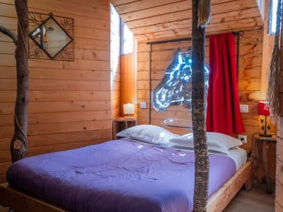Cabane en bois avec un lit double et des éléments décoratifs en bois naturel.