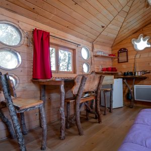 Cabane en bois dans les arbres, intérieur chaleureux avec des meubles en rondins.
