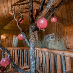 Cabane dans les arbres en Nouvelle-Aquitaine avec des décorations lumineuses rouges.