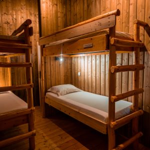 Chalet en bois avec lits superposés, ambiance chaleureuse et lumineuse.