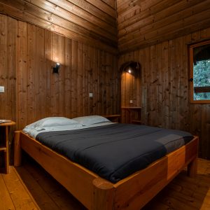 Chalet en bois chaleureux avec lit double et murs en bois naturel.