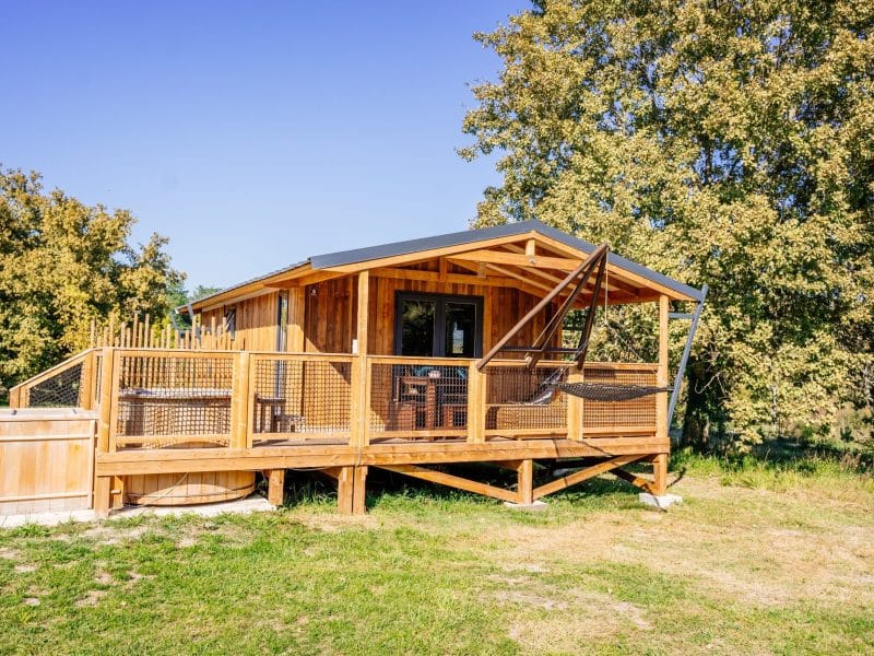 Cabane en bois avec terrasse et jacuzzi, nichée dans la nature en Aquitaine.