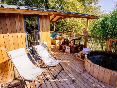 Cabane en bois avec terrasse, chaises longues et baignoire en bois, Aquitaine.