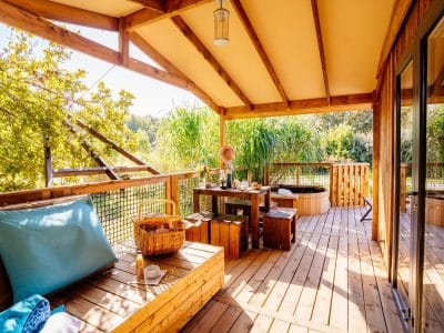Cabane en bois avec terrasse ensoleillée et jacuzzi, au cœur de la nature en Aquitaine.