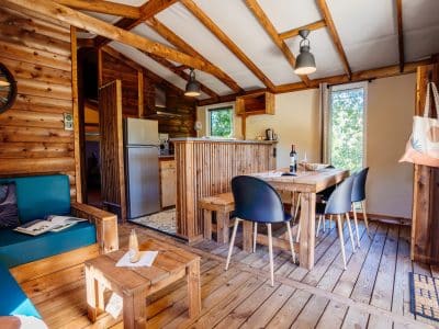 Cabane en bois à Aquitaine, intérieur chaleureux avec meubles en bois et lumière naturelle.