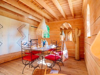 Hébergement insolite en Aquitaine : cabane en bois avec table et chaises colorées.