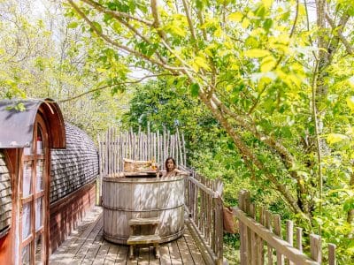Cabane perchée en Aquitaine avec un bain nordique entouré de verdure.