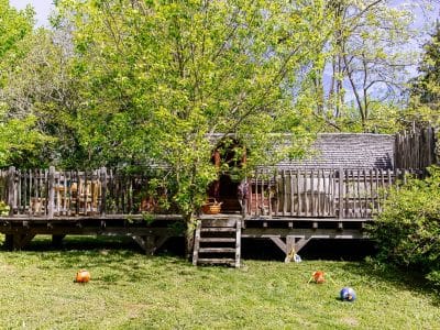 Cabane perchée en Aquitaine, entourée darbres verdoyants et dun jardin accueillant.