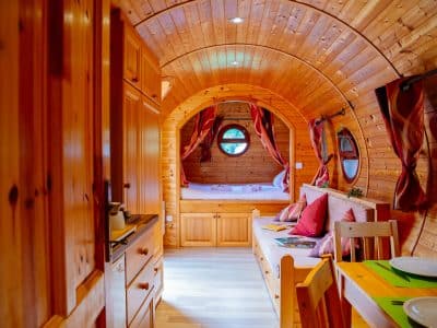 Hébergement insolite en Aquitaine : roulotte en bois avec fenêtres rondes et décor chaleureux.