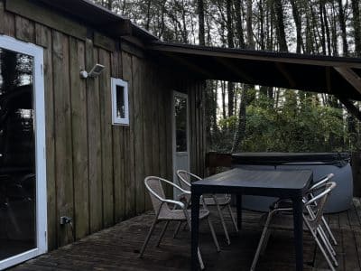 Cabane en bois avec terrasse et jacuzzi, entourée de verdure à Pays de la Loire.