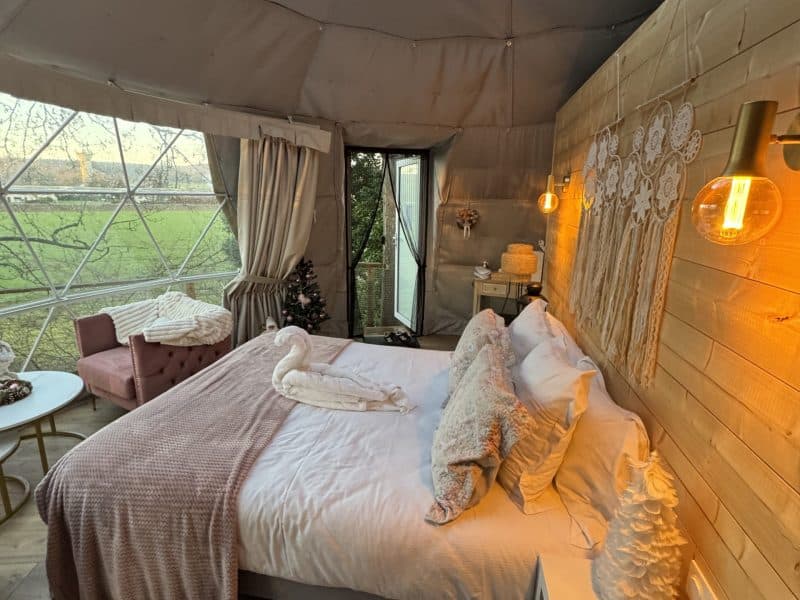 Dôme cosy avec lit douillet, décoré de lumière chaleureuse et vue sur la nature.