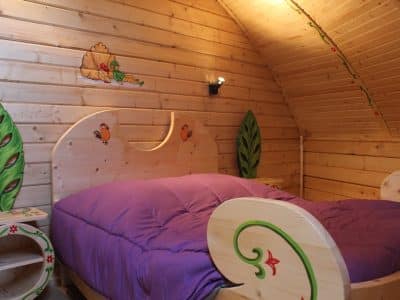 Cabane en bois colorée avec un lit douillet et des motifs ludiques sur les murs.