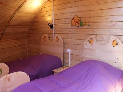 Hébergement insolite en Nouvelle-Aquitaine : chambre en bois avec lits jumeaux colorés.