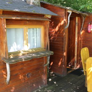 Cabane en bois dans les arbres, avec une terrasse en bois et des détails naturels.