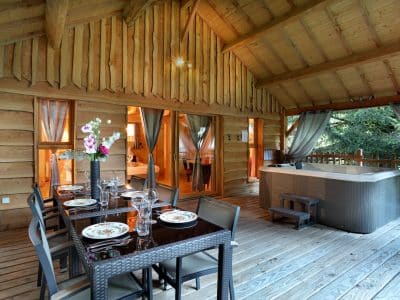Cabane en bois avec jacuzzi, terrasse spacieuse et décoration chaleureuse.