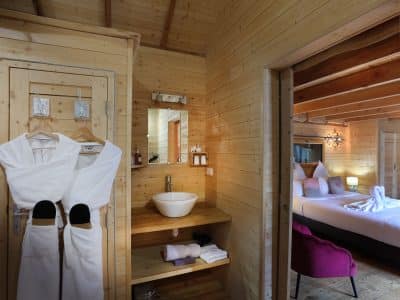 Chalet en bois chaleureux avec salle de bain moderne et lit douillet.