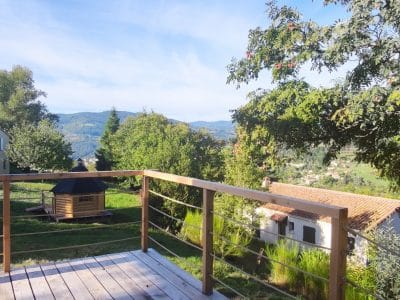 Cabane perchée avec terrasse en bois, vue panoramique sur les montagnes verdoyantes.