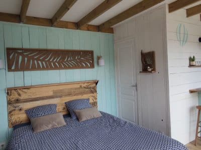 Chambre cosy en bois avec lit douillet et murs turquoise, en Auvergne-Rhône-Alpes.