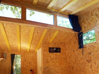 Cabane en bois lumineuse avec grandes fenêtres et décoration naturelle.
